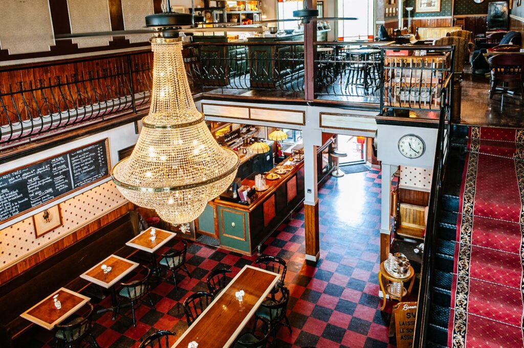 Cardinal Tea Room with a huge chandelier and a staircase to the second floor